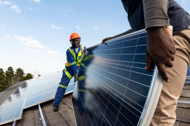 Team of blue collar workers installing solar panel on roof of building